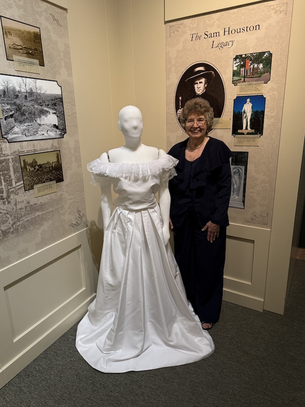 Alumna Patricia Cude poses next to a replica of Nannie Houston's wedding dress, which she recreated for the second time in 65 years.